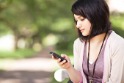 Photo of a woman sitting in a park and looking at her phone.